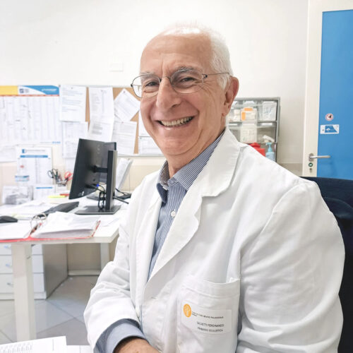 Il dottor Ferdinando Salvetti, primario di oculistica, sorride nel suo studio in camice bianco.